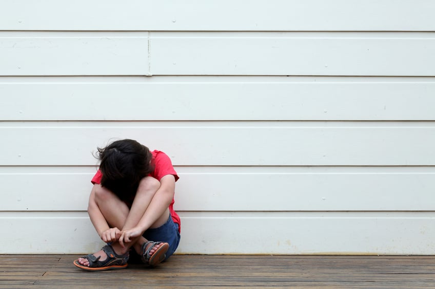 young boy sitting and hiding his face