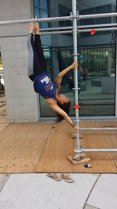 Michelle Abbruzzese performing pole tricks on some scaffolding