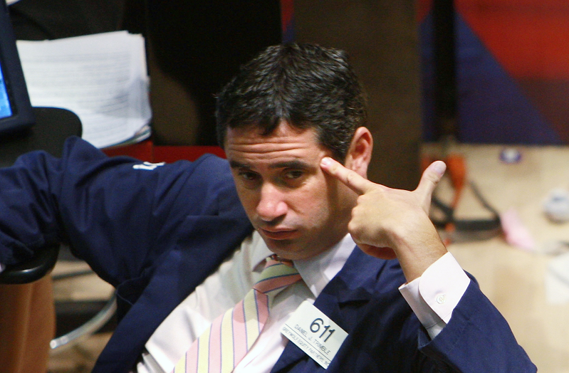trader puts his finger to his head on the floor of the New York Stock exchange