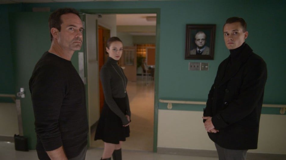 The leads of Wayward Pines stand together in a hallway, looking out into the distance ominously