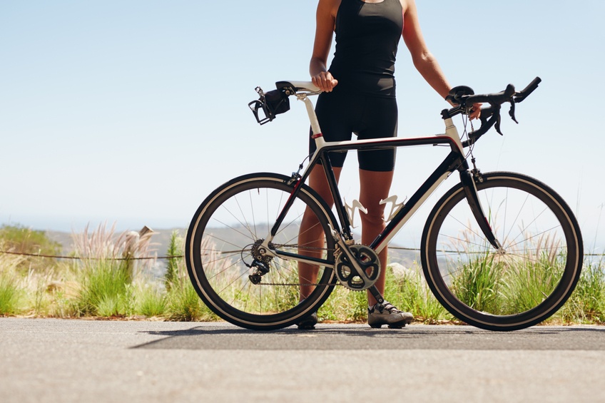 woman standing on the side of the road with her bike