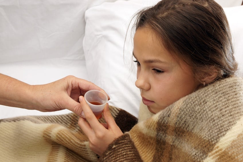 Girl taking cough syrup in bed Girl taking cough syrup in bed