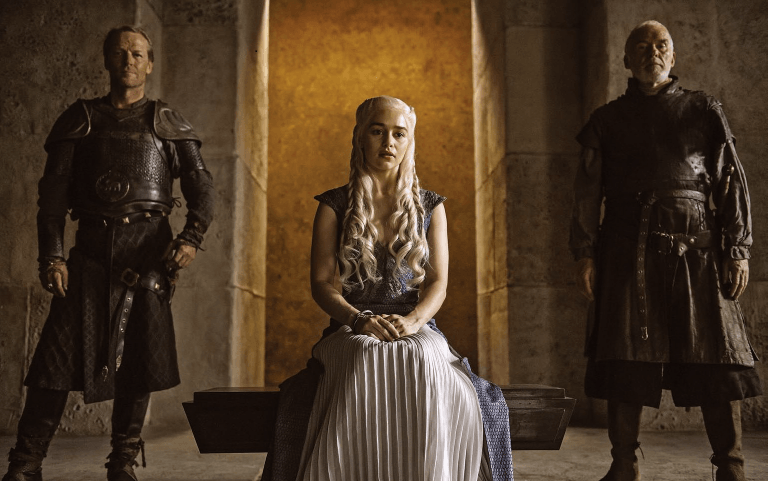 Emilia Clarke sitting between two men. Emilia Clarke sitting between two men.
