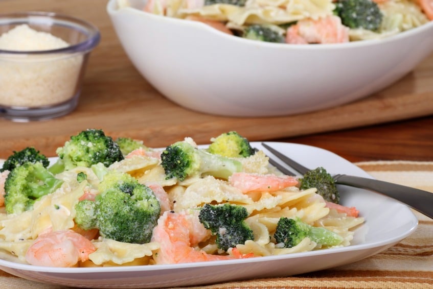 Shrimp with pasta and broccoli with a sauce on a plate
