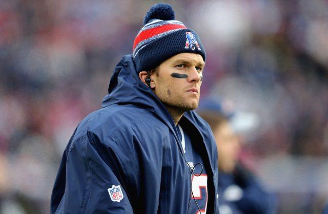 Tom Brady wearing a blue jacket and beanie on the baseball field. Tom Brady wearing a blue jacket and beanie on the baseball field.