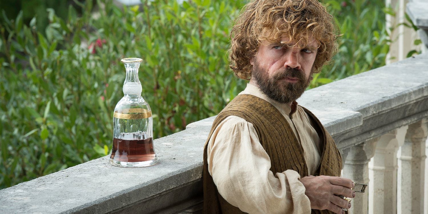 Tyrion Lannister leaning against a railing, with a carafe of wine sitting next to him