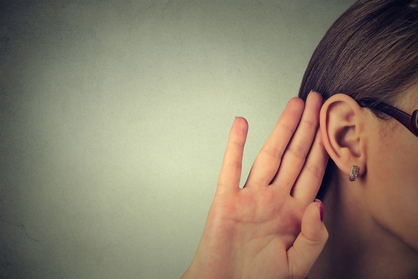 Woman holds her hand near ear