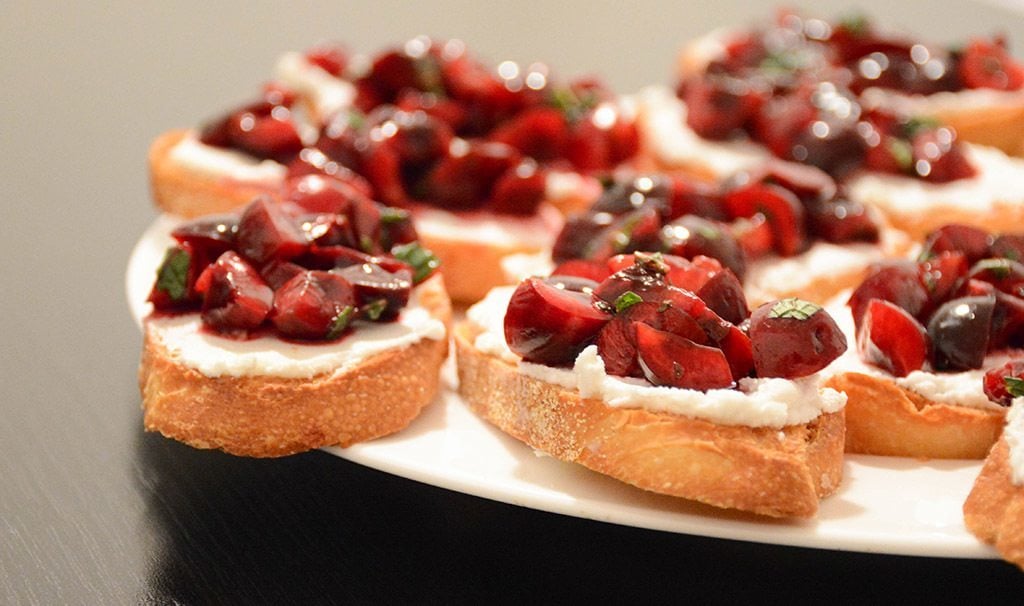 white plate filled with cherry and goat cheese crostini