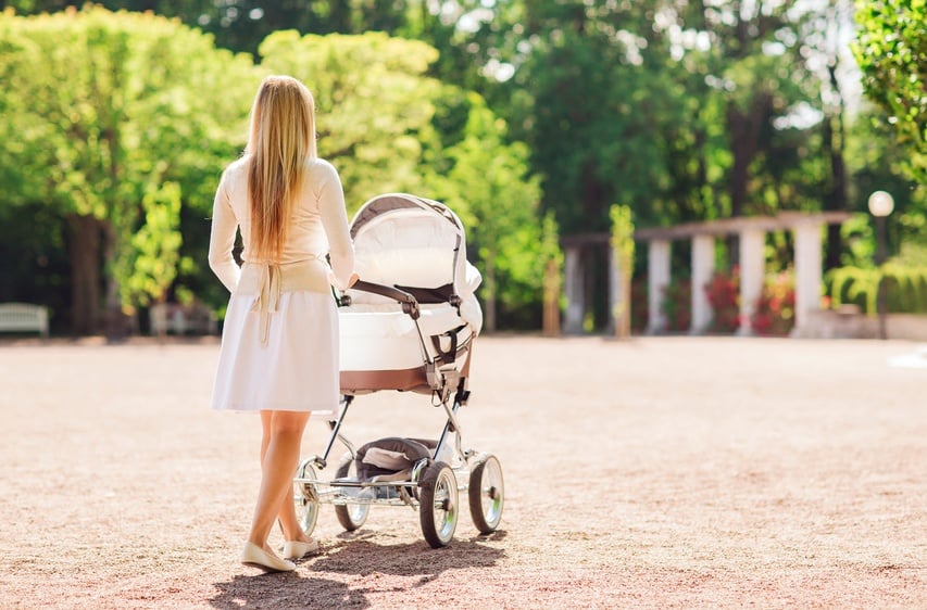 young mother pushing a stroller as she walks