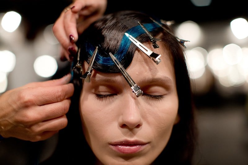 MADRID, SPAIN - FEBRUARY 15: A hairdresser places on a model a blue dyed natural extension at the Mercedes Benz Fashion Week make-up and hairdresser backstage on February, 15, 2014 in Madrid, Spain. Each model shows a dyed hair natural extension fixed with the main color of the designs she is going to wear. Blues, greens, oranges and pinks form the chromatic palette of Maria Barros new collection. Maria Barros (A Coruna, Spain) is one of the most recognized young talents in the Spanish fashion design. Since 2009 she has been launching her collections in the Madrid Fashion Week. For this winter edition Maria has presented 17 designs of her Autumn/ Winter 2014/15 Collection.