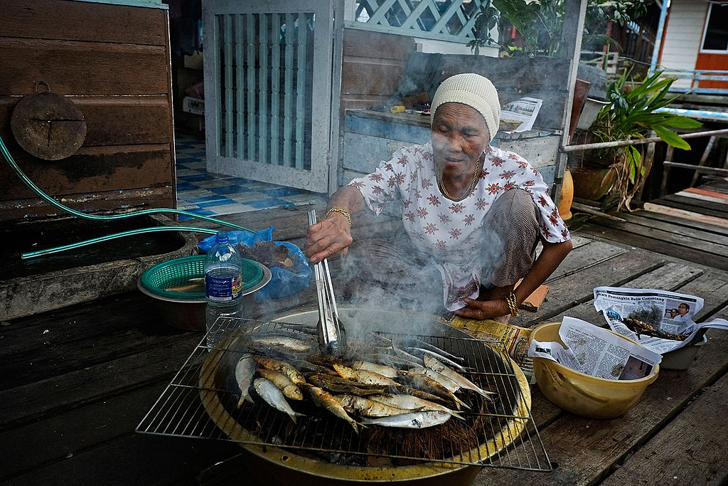 A muslim woman cooks fresh fish in Brunei