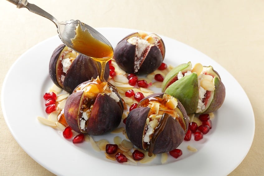 Figs with goat cheese and honey on a white plate