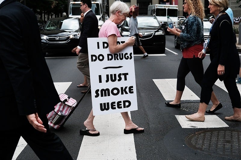 A female cannabis consumer walks with a sign supporting legalizing marijuana