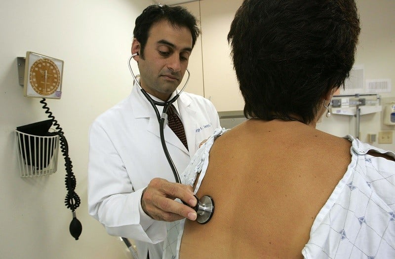 A doctor examines a patient with health insurance, a visit that would otherwise cost bundles