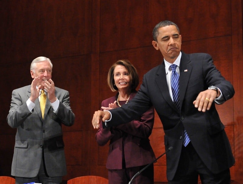 President Barack Obama motions for everybody to sit down before delivering remarks to the House Democratic Caucus retreat at the U.S. Capitol Visitors Center January 14, 2010