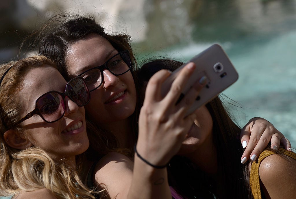 Tourists take a selfie in front of the Trevi fountain in Rome