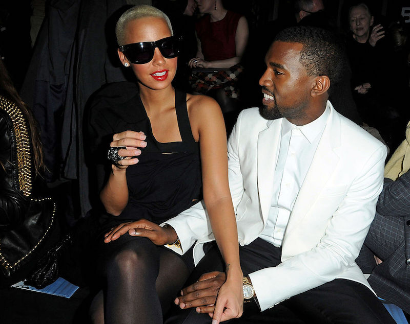 Kanye West and Amber Rose sit together at a fashion show.