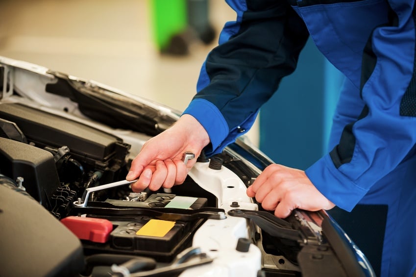 man in blue uniform repairing car