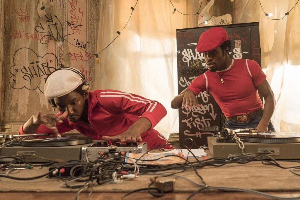 Two men in red and white spinning playing music surrounded by recording equipment Two men in red and white spinning playing music surrounded by recording equipment