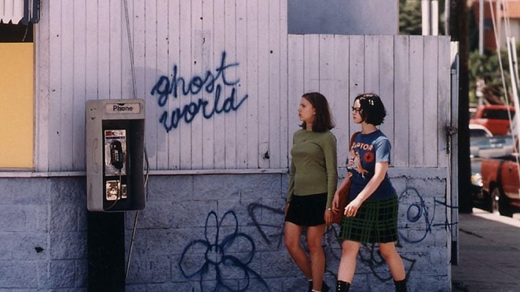 Scarlett Johansson and Thora Birch walk next to a white fence that reads "Ghost World"