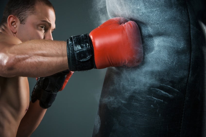 Young boxer wearing red gloves working on punching bag