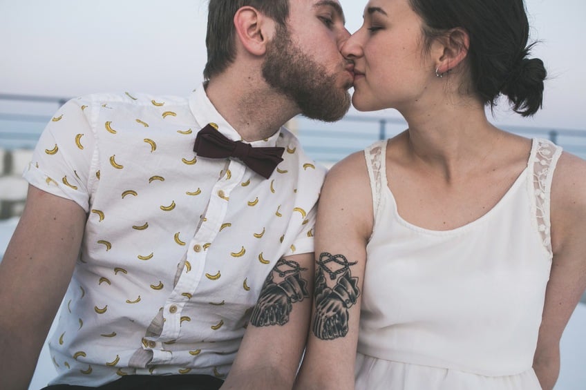 Young couple with matching tattoos kissing Young couple with matching tattoos kissing