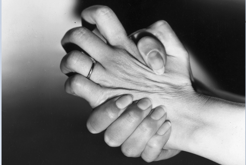 A woman nervously wrings her hands