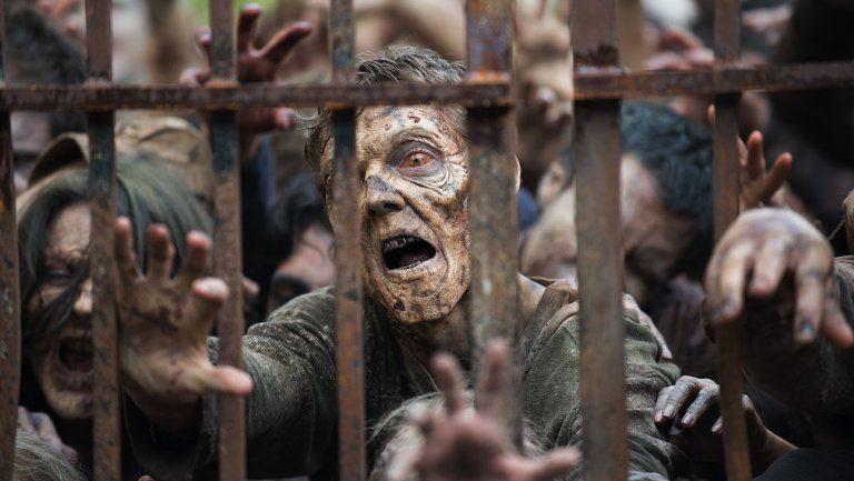 A group of zombies pile up against a fence in AMC's The Walking Dead