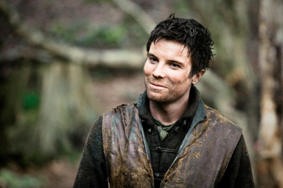 In a scene from Season 2 of 'Game of Thrones,' Gendry smiles while standing in a forest.