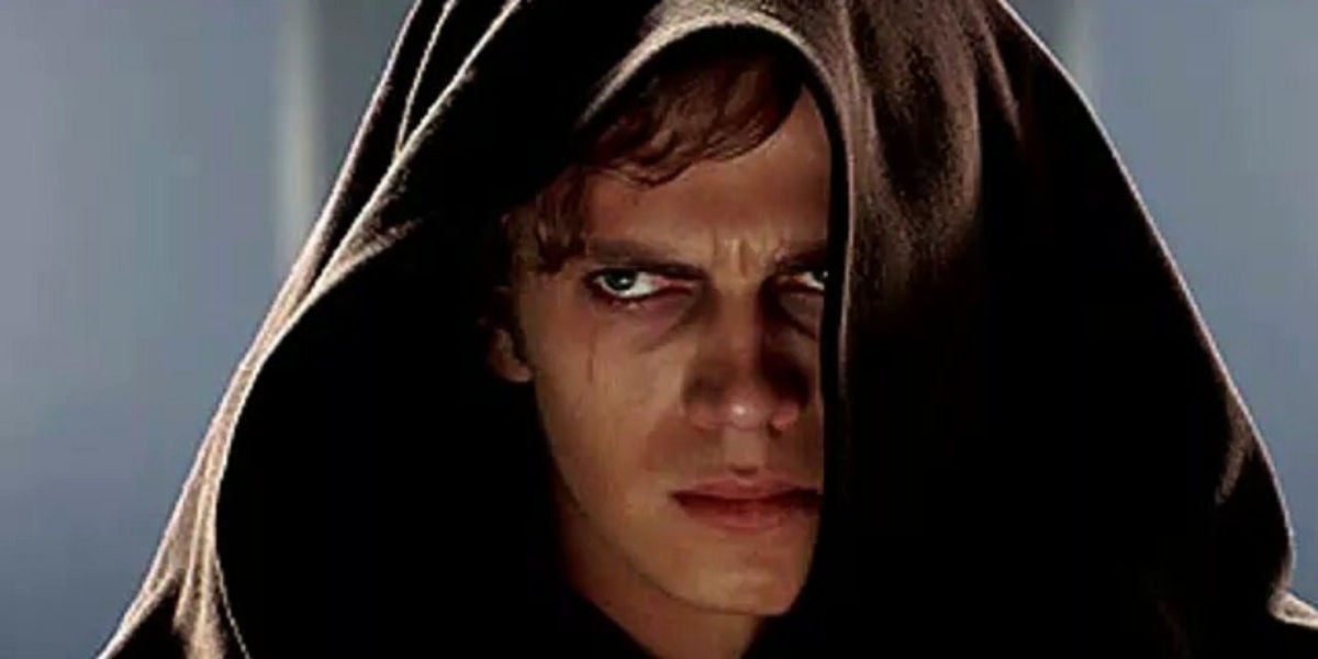 Actor Hayden Christensen looking glum in a hooded cloak as Anakin.