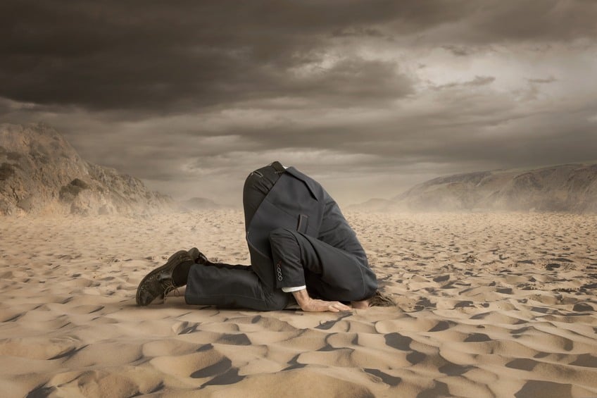 businessman hiding head in the sand