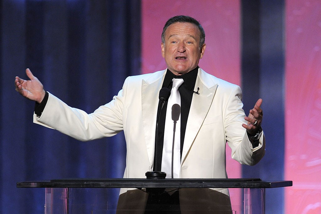 Robin Williams speaks onstage in a white suit