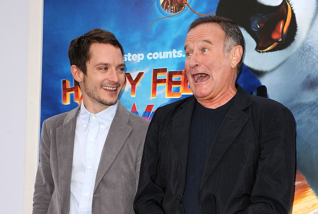 Elijah Wood and Robin WIlliams in front of a Happy Feet poster