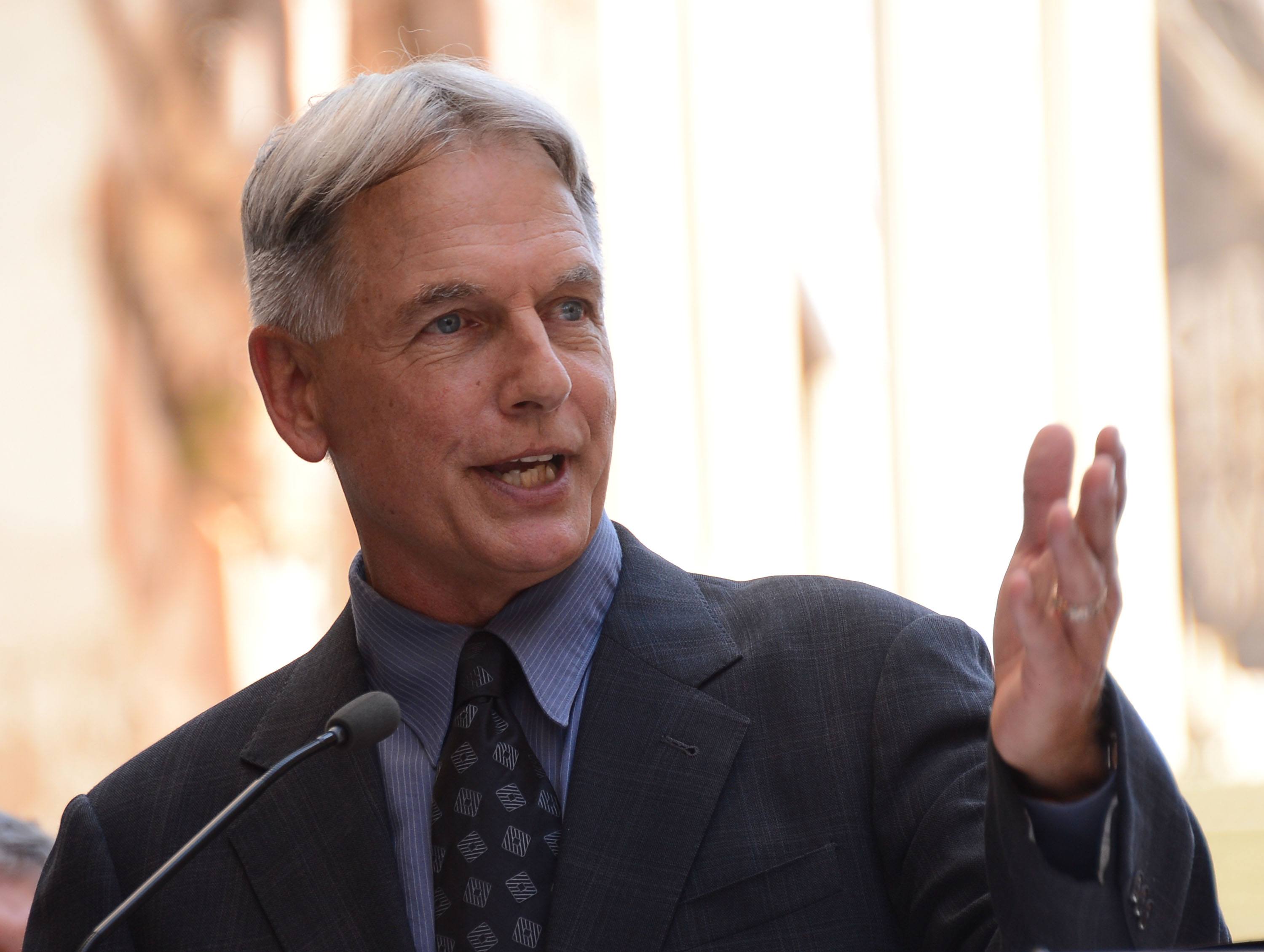 Mark Harmon speaking in front of a microphone. Mark Harmon speaking in front of a microphone.