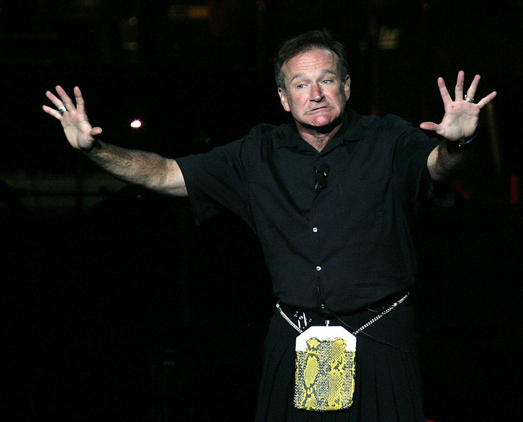 Robin Williams performs onstage with his hands up
