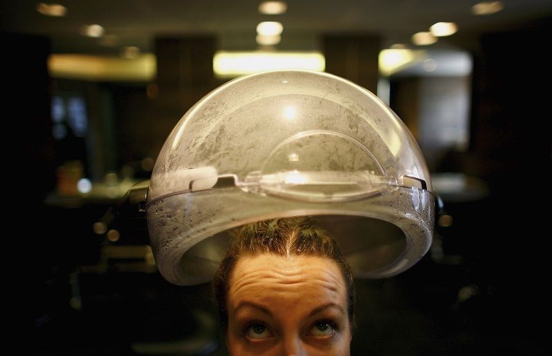 A woman has her hair steamed at a salon