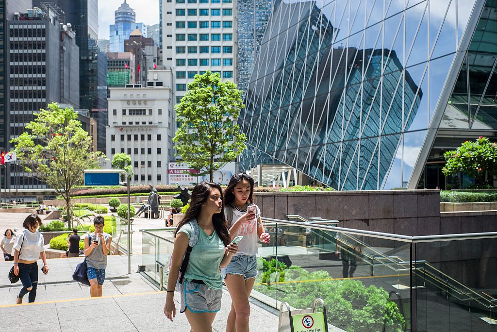 A girl uses her phone while strolling through Hong Kong