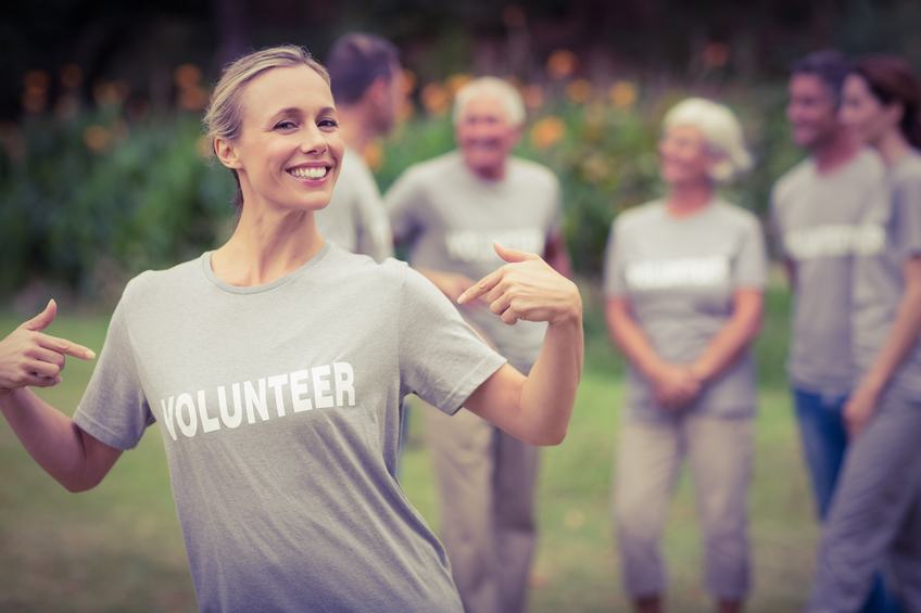 Happy volunteer showing her t-shirt to camera on a sunny day Happy volunteer showing her t-shirt