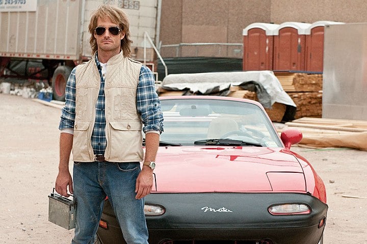 A man stands in front of a red car. A man stands in front of a red car.