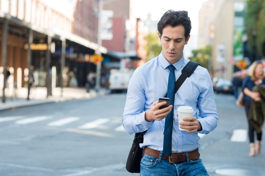 Businessman using smartphone and holding paper cup