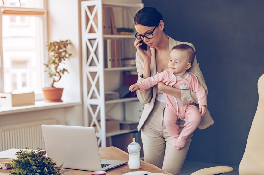 beautiful businesswoman talking on mobile phone while standing with her baby girl