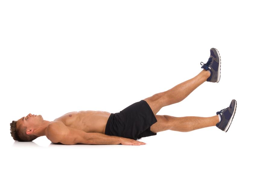 Muscular man lying on a floor and does a scissors stomach exercise