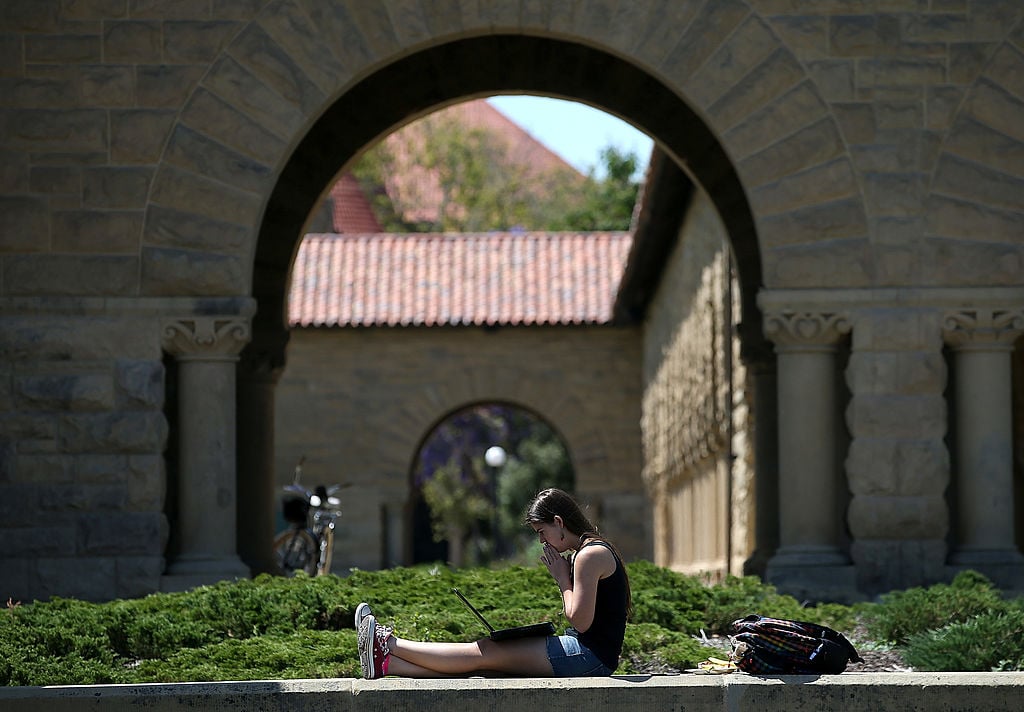 A woman works on a laptop on the Stanford University campus