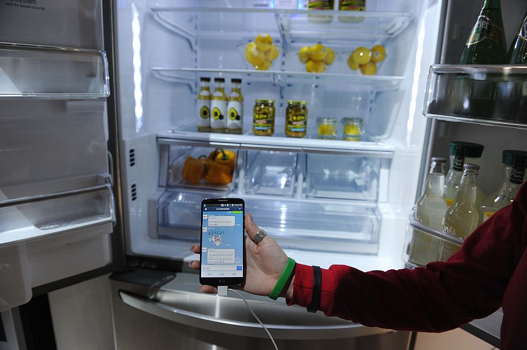 a smartphone with Home Chat in front of an LG smart refrigerator