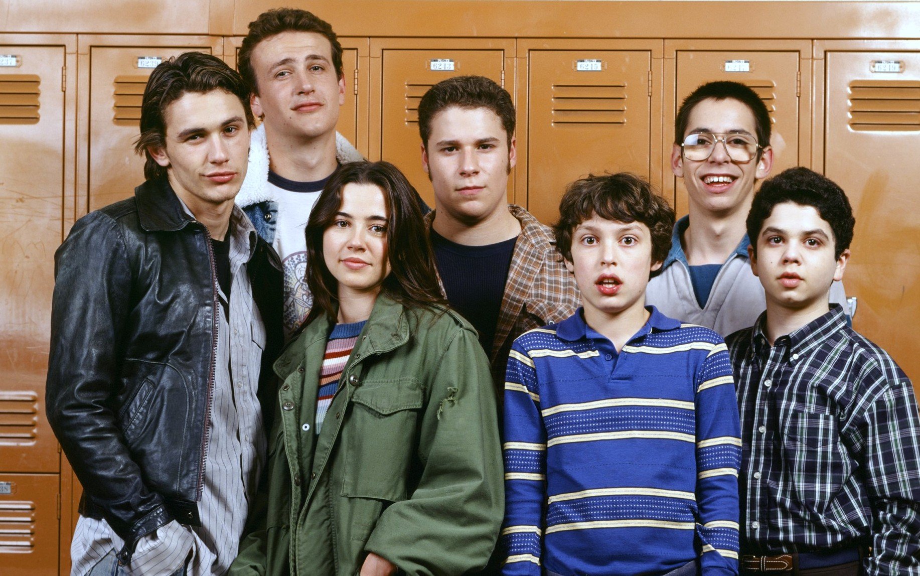 The cast of 'Freaks and Geeks' are standing together in front of orange lockers.