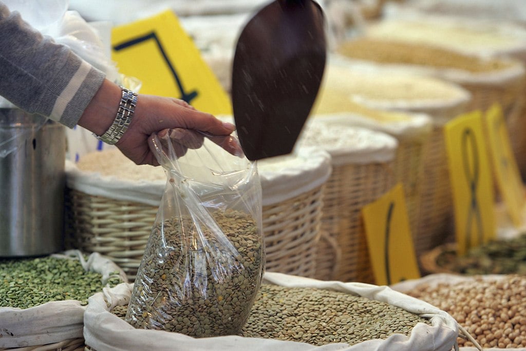 scooping lentils from a bulk container