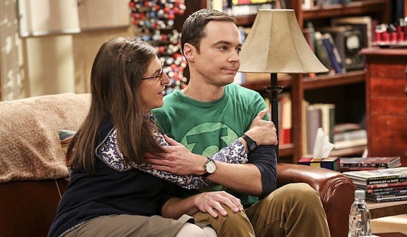 Amy and Sheldon hug on a couch in The Big Bang Theory