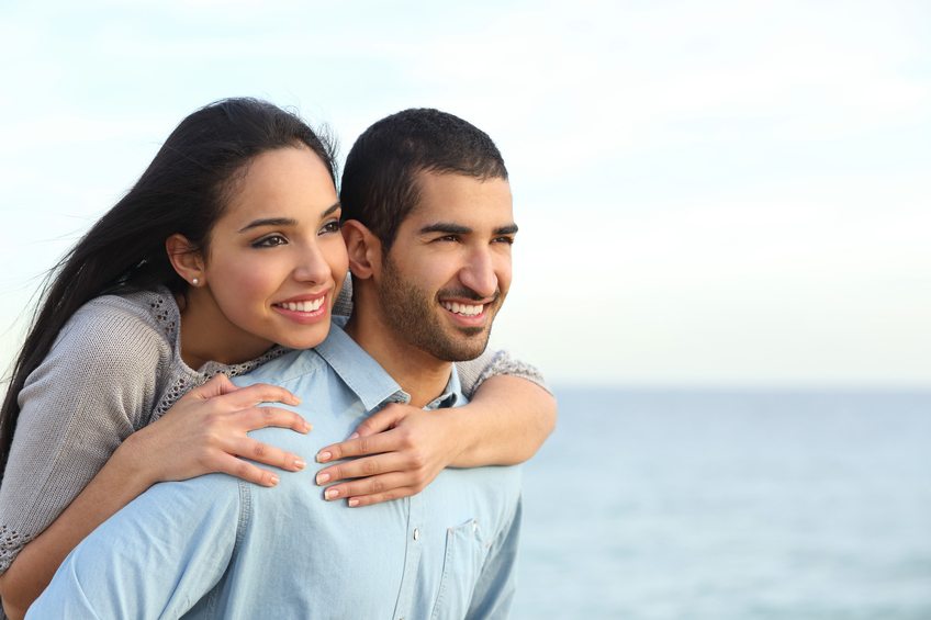 Arab couple flirting piggyback in love on the beach