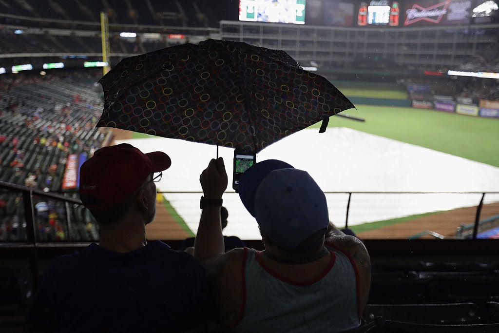Fans look at the weather radar on a smartphone during a rain delay