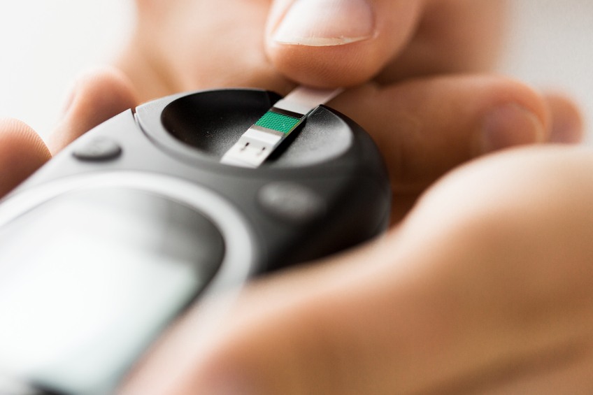 man checking blood sugar level by glucometer